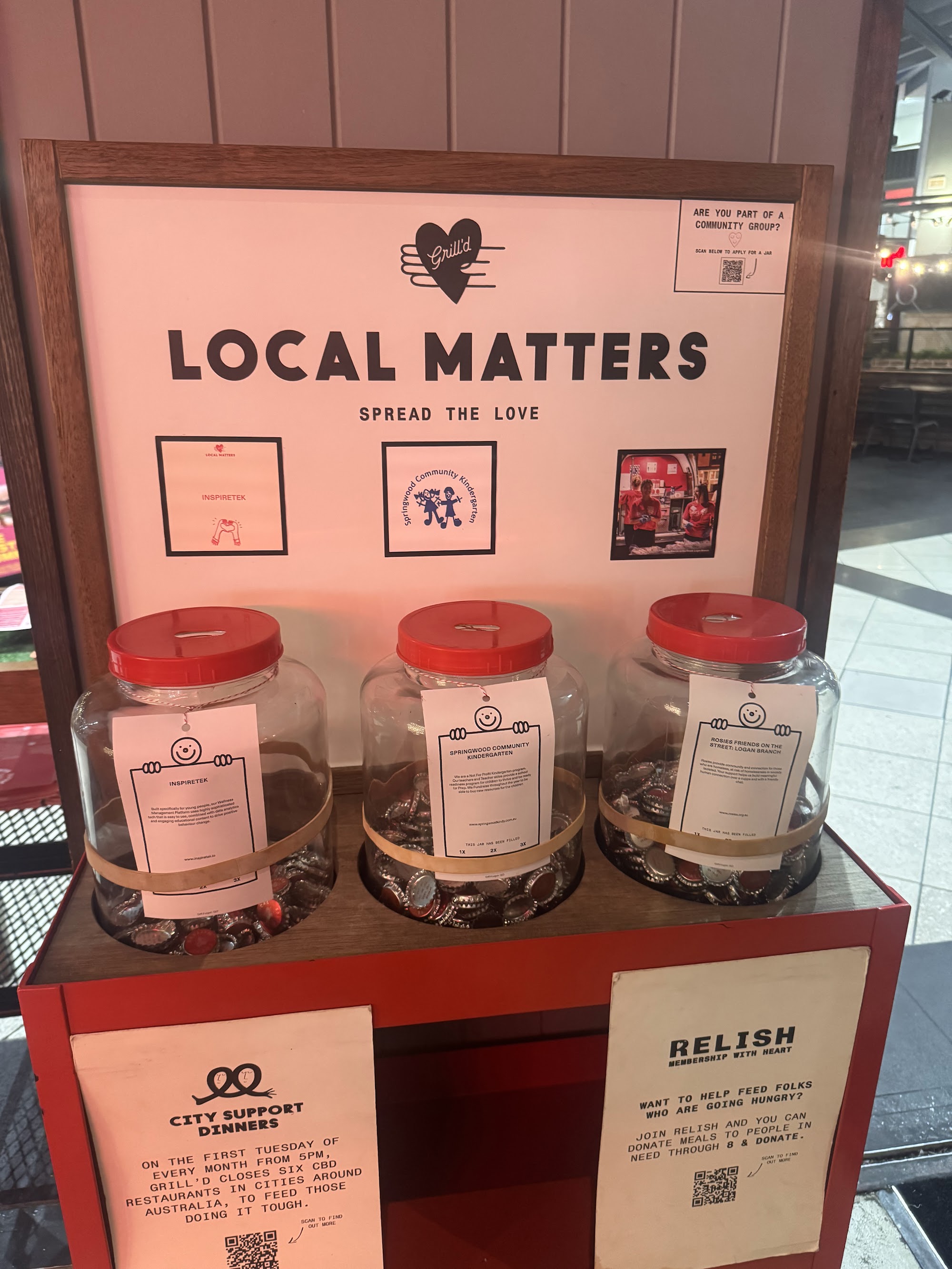 Local Matters donation jars on display inside a Grill'd restaurant