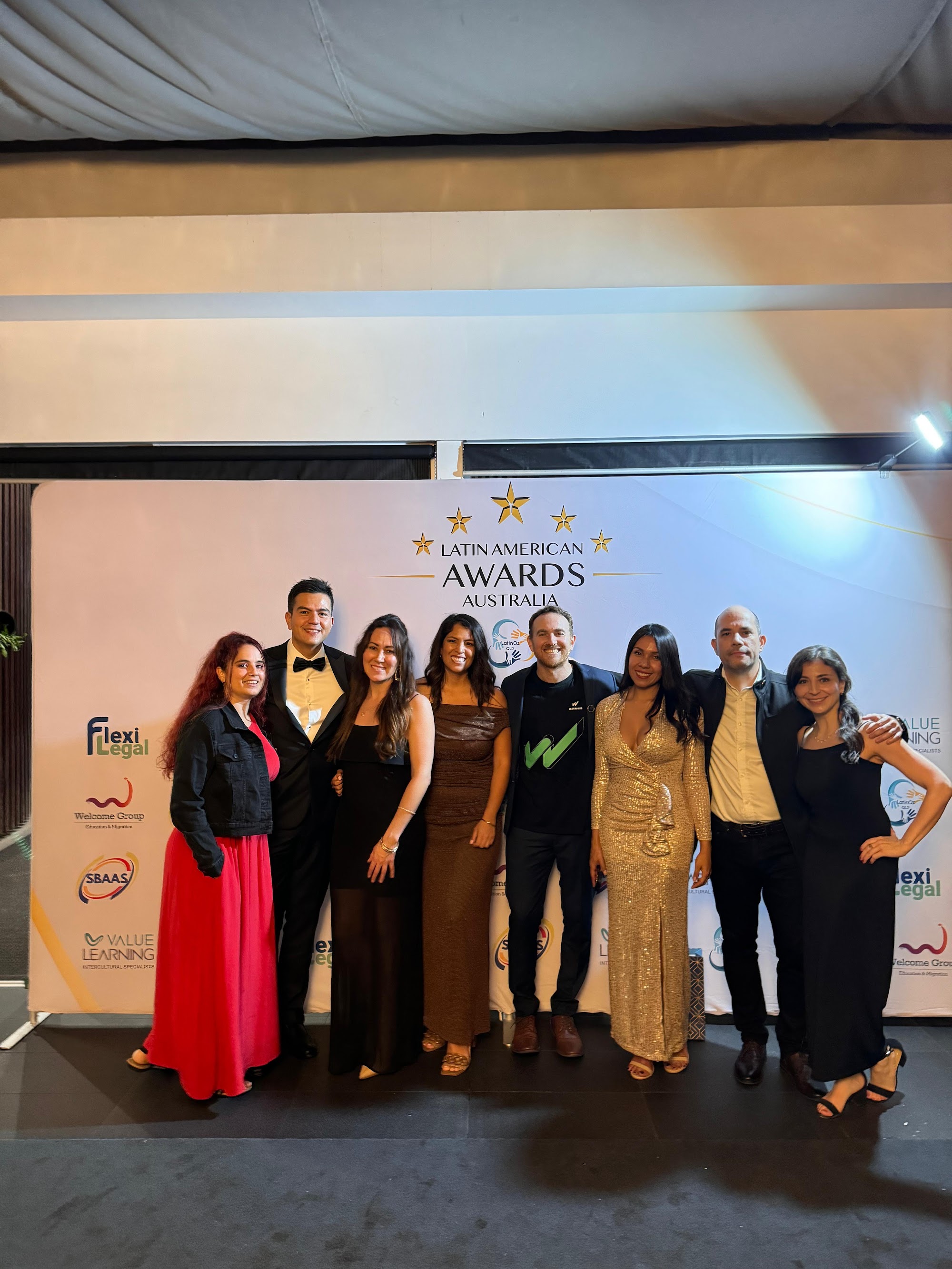 Warriors team members posing at the Latin American Awards Australia step-and-repeat backdrop